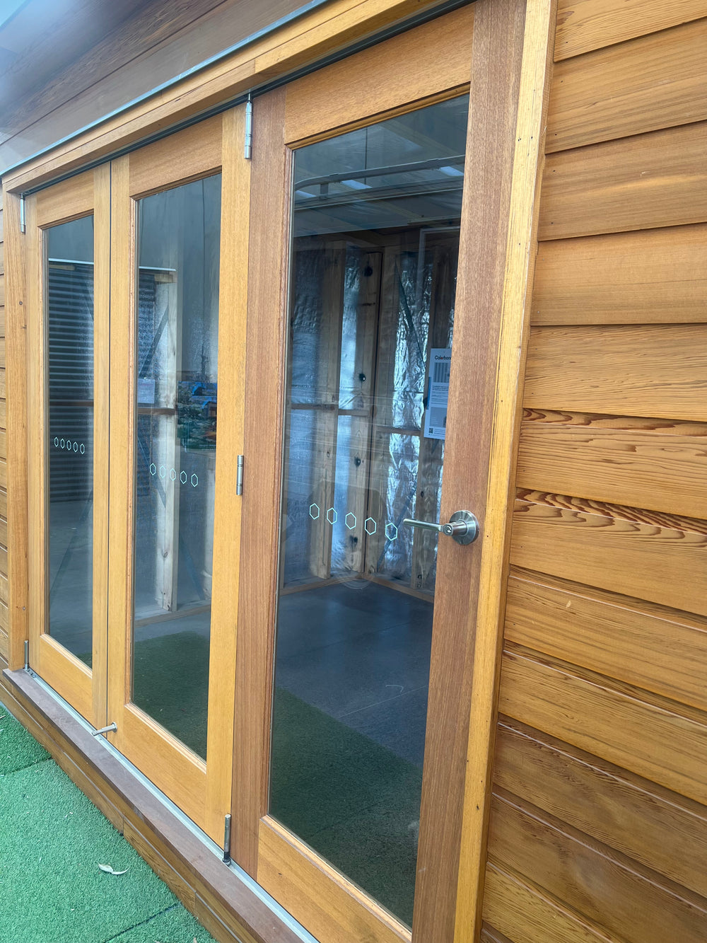 Close-up of timber-framed double-glazed bifold doors on a backyard studio — enhancing energy efficiency, sound insulation, and comfort in garden office pods.