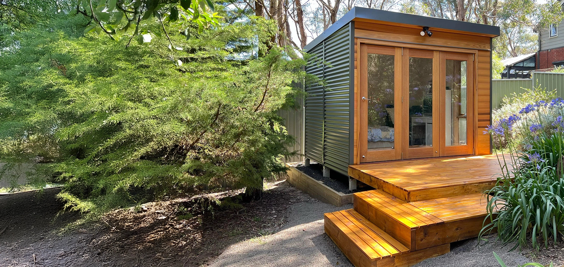 The Hideaway garden studio with timber steps and Colorbond cladding, set in a landscaped backyard. Ideal for a backyard office, artist’s retreat, or compact DIY studio pod.