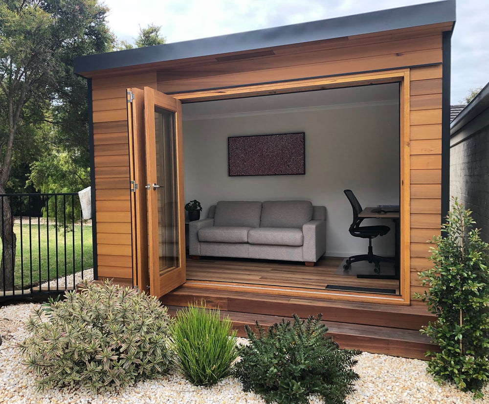 "The Hideout" backyard studio pod, 3830mm x 2490mm, 9.5m2, with bifold doors, western red cedar on the front of the building, and colorbond on the side and back walls. Set up as a home office.