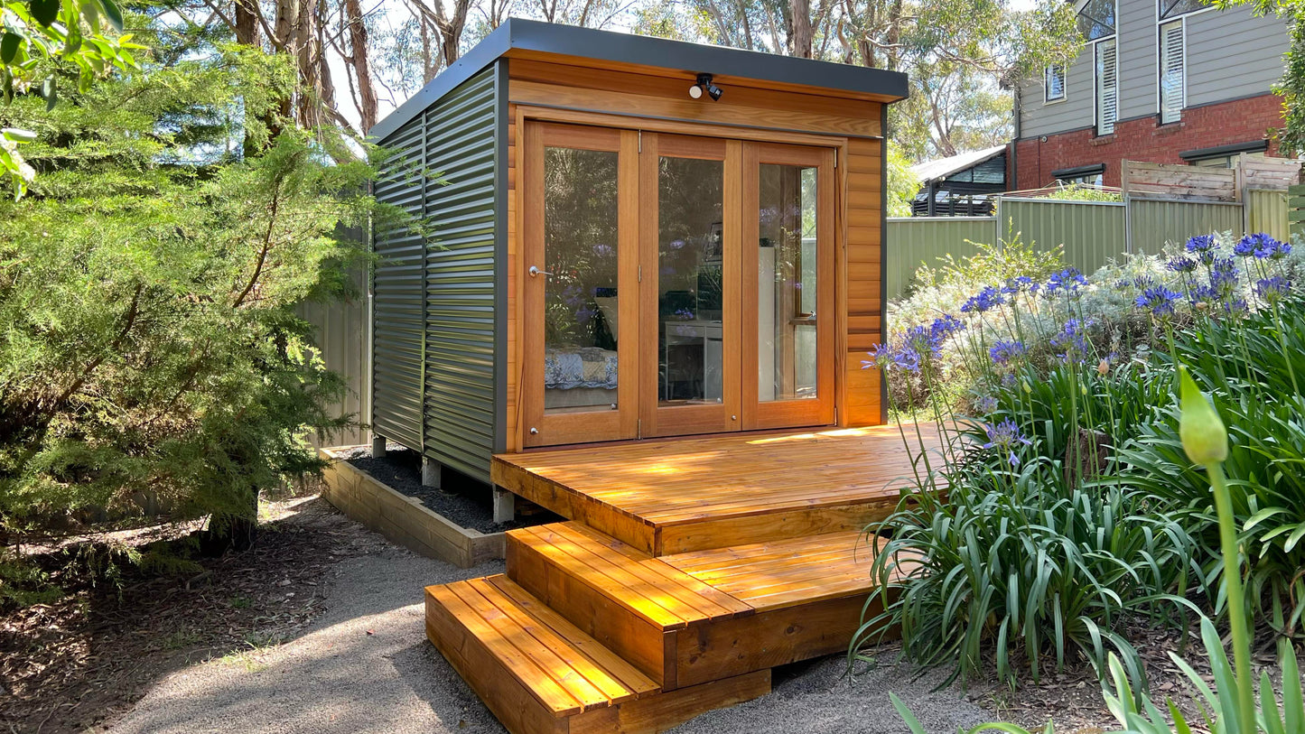 The Hideaway garden studio with timber steps and Colorbond cladding, set in a landscaped backyard. Ideal for a backyard office, artist’s retreat, or compact DIY studio pod.