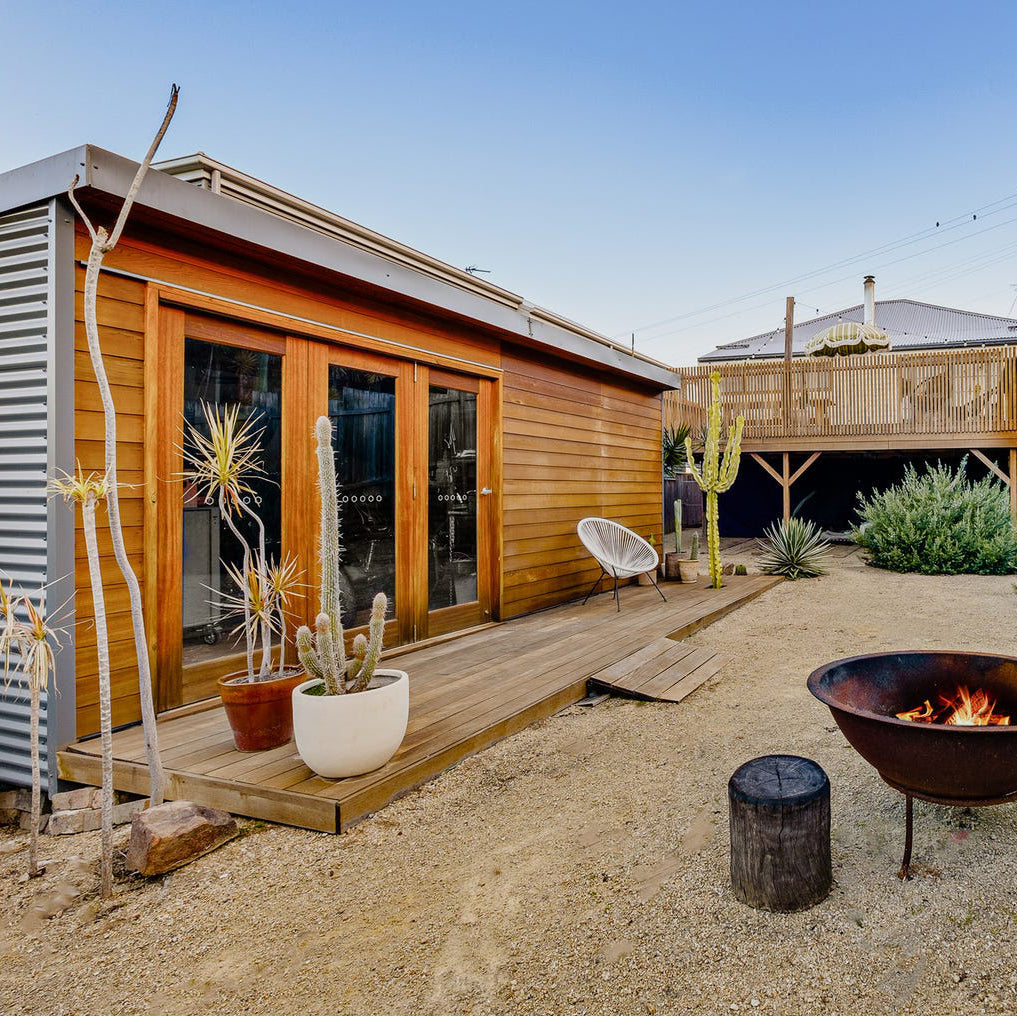 The Haven backyard studio with Western Red Cedar cladding, timber deck, and desert landscaping — modern garden room with bi-fold doors and fire pit feature.